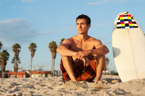 Surfer zittend op het strand met surfboard — Stockfoto