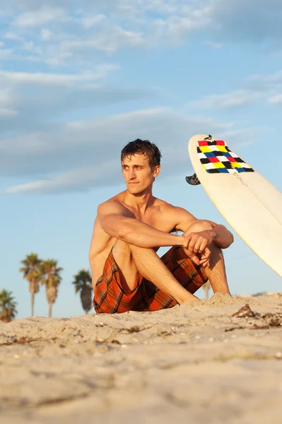 Surfer zittend op het strand met surfboard — Stockfoto