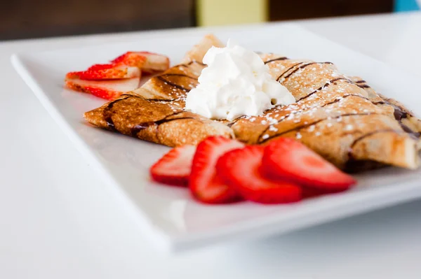 Crêpe mit frischen Erdbeeren bestreut mit Zucker lizenzfreie Stockfotos