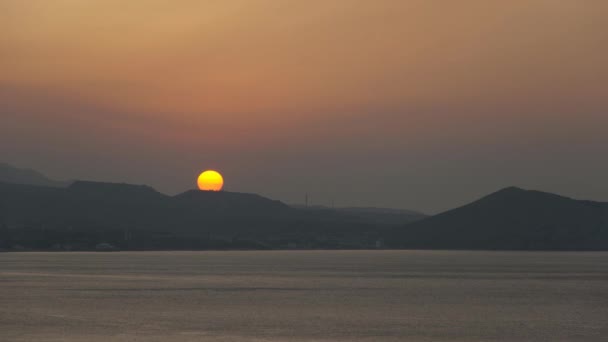 Солнце встает из-за горы на берегу моря, с течением времени — стоковое видео