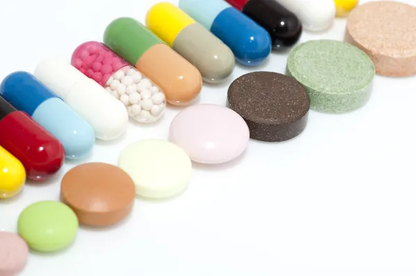 Verschillende capsules en tabletten in rij — Stockfoto