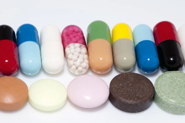 Verschillende capsules en tabletten in rij — Stockfoto