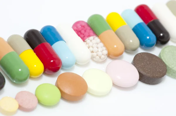 Verschillende capsules en tabletten in rij — Stockfoto