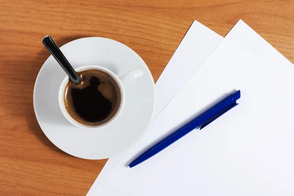 Taza de café en mesa con papeles y pluma Imagen de stock