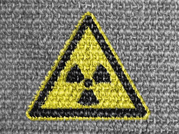 Nuclear radiation sign drawn on grey fabric — Stock Photo, Image