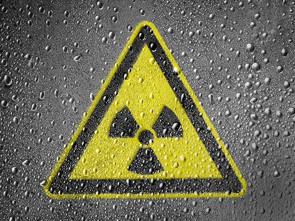 Nuclear radiation sign drawn on metal surface covered with rain drops — Stock Photo, Image