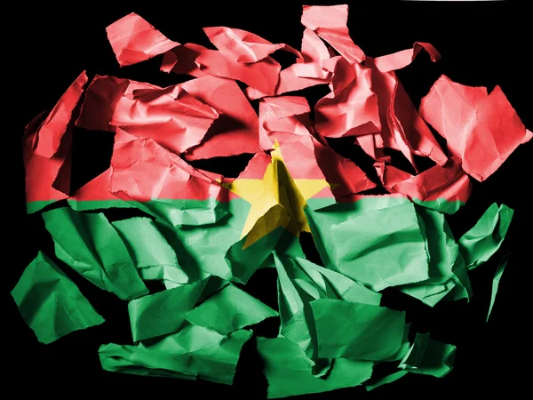 Burkina faso bandery malowane na kawałki papieru rozdarty na czarnym tle — Zdjęcie stockowe