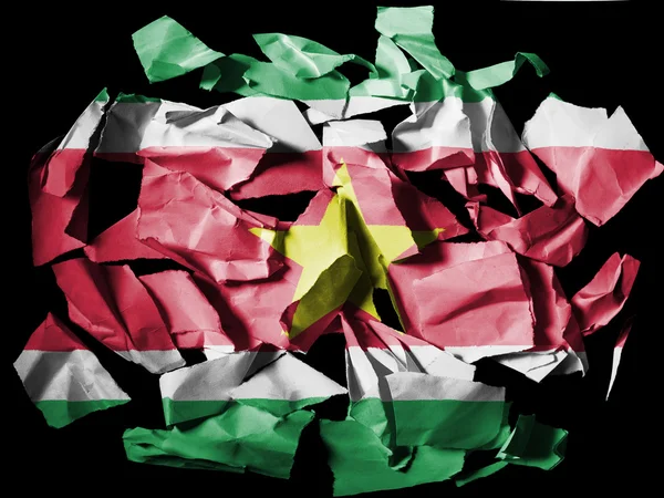 Bandera surinamesa pintada sobre trozos de papel desgarrado sobre fondo negro — Foto de Stock