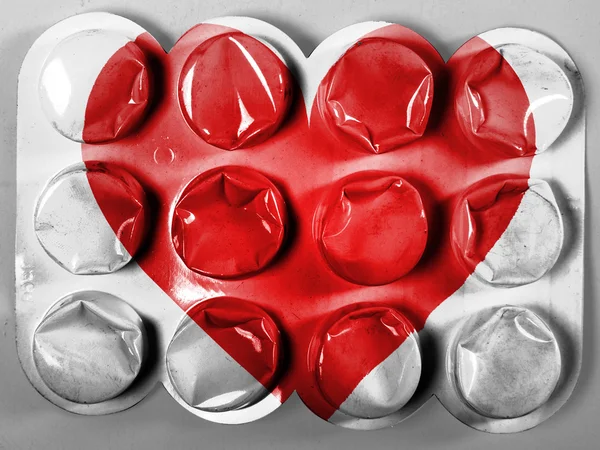 Red Heart symbol painted on painted on tablets or pills — Stock Photo, Image