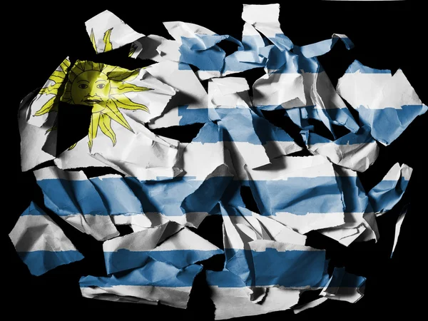 Bandiera Uruguay dipinta su pezzi di carta strappata su sfondo nero — Foto Stock