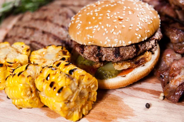 Burger with corn on wooden board — Stock Photo, Image