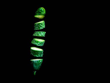 Siyah arkaplanda yüzen kesilmiş salatalık