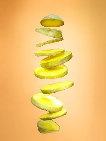 Slices of potato floating on orange background Stock Photo