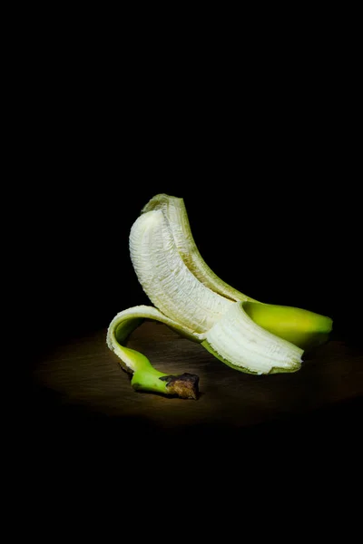 Peeled banana on wooden board black background Royalty Free Stock Images