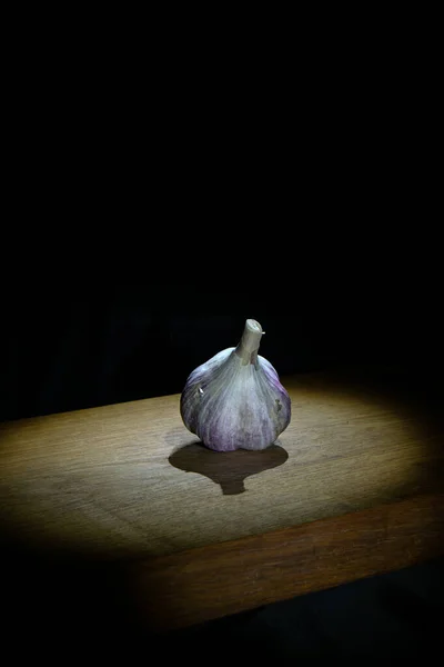 Garlic on wooden board on dark background Stock Photo