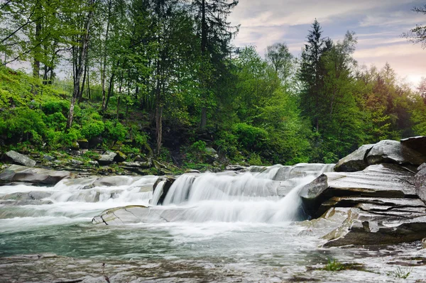 Rauer Gebirgsfluss mit weißem Schaum fließt zwischen den Felsen und — Stockfoto