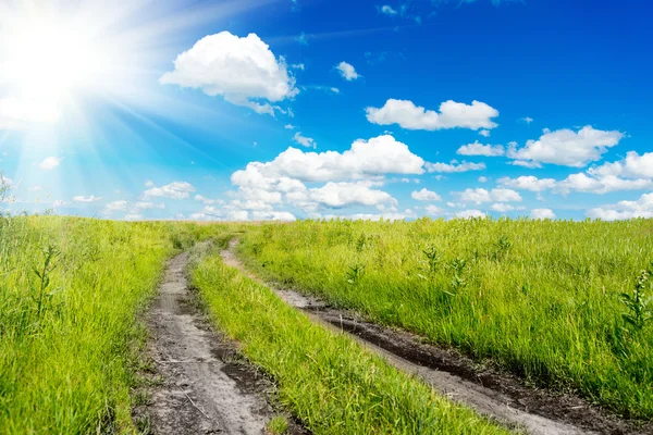 Paisagem rural tranquila e ensolarada em amplo campo com estrada rural — Fotografia de Stock