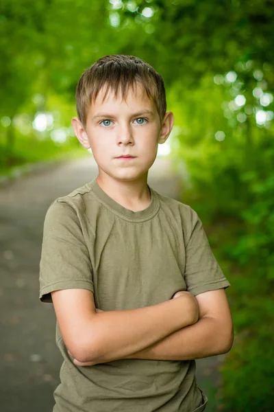 Close-up portrait of serious little boy with folded hands outdoo — Stock Photo, Image