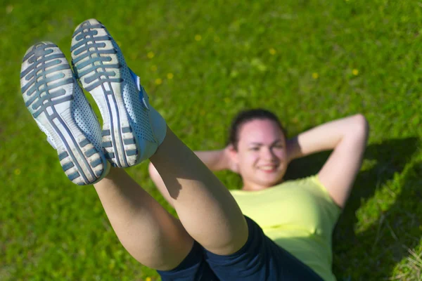 Happy young woman doing exercise on green grass — Stock Photo, Image