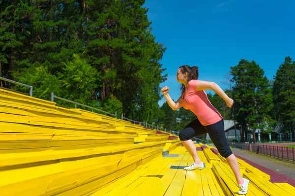 Ung kvinna gör övning på stadion — Stockfoto