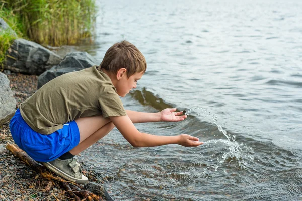 Retrato de cerca de un niño serio sentado cerca del río —  Fotos de Stock