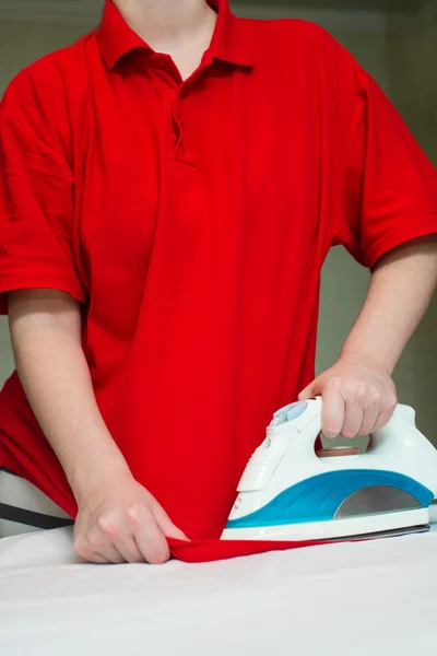 Närbild av kvinnans hand Strykningsservice hennes t-shirt — Stockfoto