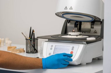 Teknisyen, diş laboratuarında protez seramik dişler pişirmek için yüksek sıcaklıkta fırın kullanıyor..