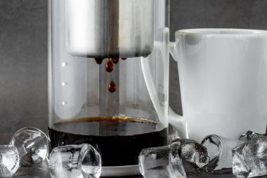 Modern Cold brew damlalı kule kahve makinesi koyu taştan arka planda.