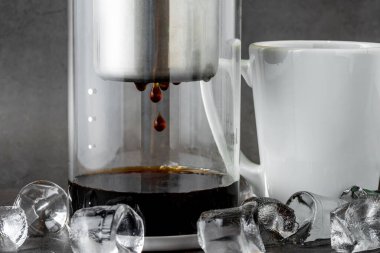 Modern Cold brew drip tower coffee maker on dark stone background clipart