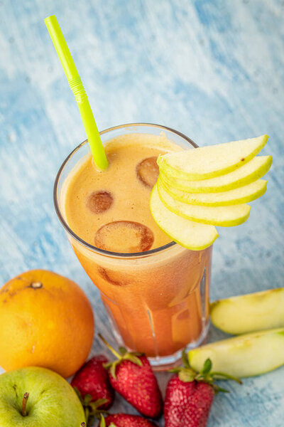 Energizing and refreshing apple, strawberry and orange mix juice on blue stone background