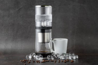Modern Cold brew damlalı kule kahve makinesi koyu taştan arka planda.