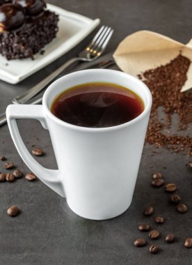 Amerikan kahvesini taş masada beyaz porselen bardakta rahatlatıyor.