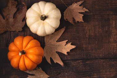 Sonbahar yapraklarının ve ahşap arka planda küçük balkabaklarının üst görüntüsü