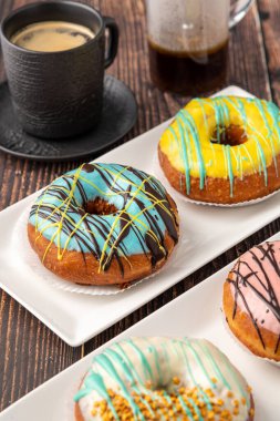 Tahta sehpada kahve olan dört farklı çörek.