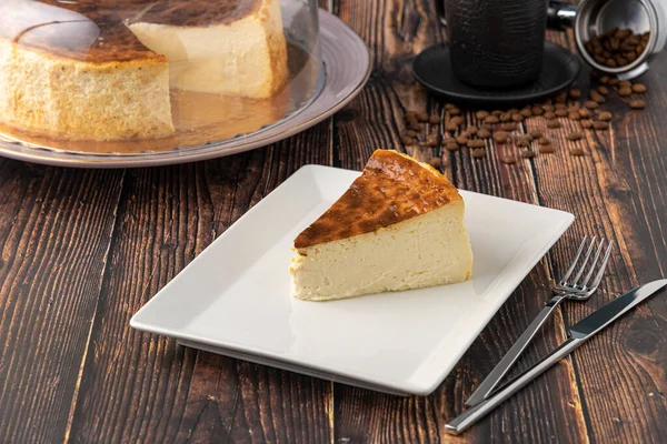 木製のテーブルの上にコーヒーとスライスサンセバスチャンチーズケーキ — ストック写真