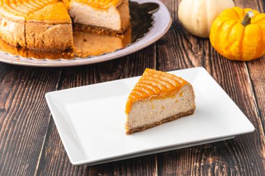 Tahta masadaki beyaz tabakta lezzetli balkabaklı cheesecake