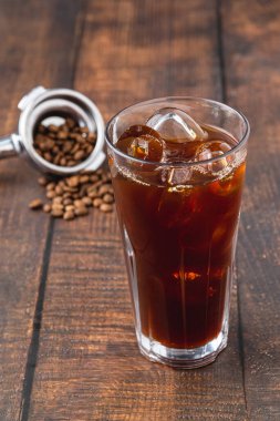 Kahve dükkanındaki ahşap bir masaya buz küplü buzlu Americano kahvesi. Bir bardak kahvenin üst görüntüsü.