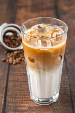 Kahve dükkanındaki ahşap bir masaya buz küplü buzlu Latte kahve.