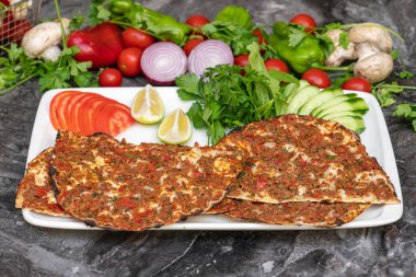 Lahmacun Türk pizzası, domates, maydanoz ve limonlu mermer masa.
