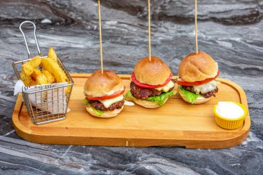 Tavuklu üç mini burger ve patates kızartmasıyla servis edilen et.