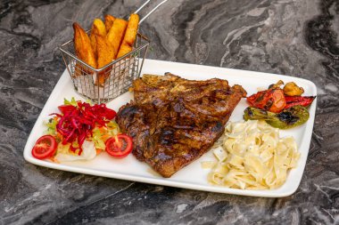 Orta pişmiş ızgara T-Bone Bifteği, patates dilimleri, brokoli ve şarap.