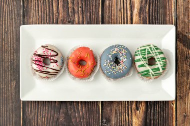 Ahşap masada kahve ile nefis renkli mini çörekler.