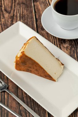 Tahta masada kahve ile dilimlenmiş San Sebastian peynirli keki.