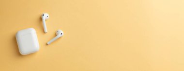 Kablosuz kulaklık ve şarj kutusu, fotoğrafın sağ tarafında boş alan bırakırken fotoğraflanmış.