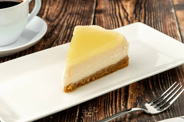 おいしいレモンチーズケーキは 木製のテーブルの上にコーヒーを添えて — ストック写真