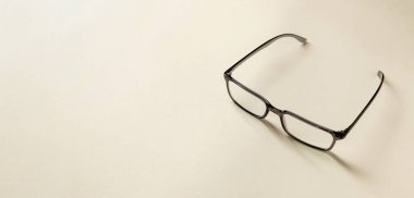 Krem rengi bir masada okuma gözlüğü manzarası. Metin için boş boşluk