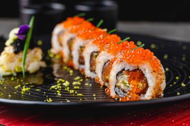 Suşi seti, siyah taştan bir tabakta çeşitli ürünler. Bulanık arkaplan ve seçici odak