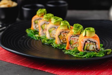 Suşi seti, siyah taştan bir tabakta çeşitli ürünler. Bulanık arkaplan ve seçici odak