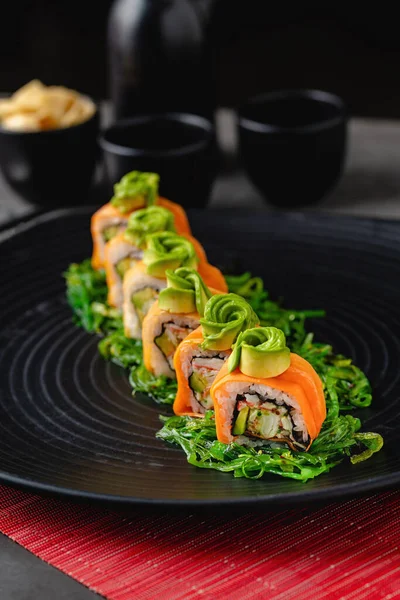 Suşi seti, siyah taştan bir tabakta çeşitli ürünler. Bulanık arkaplan ve seçici odak