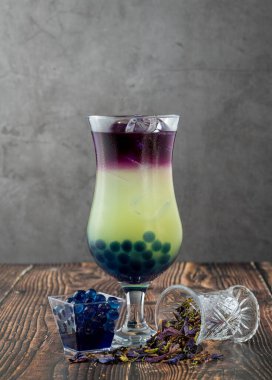 Koyu arkaplanda cam bardakta meyveli baloncuk çayı.